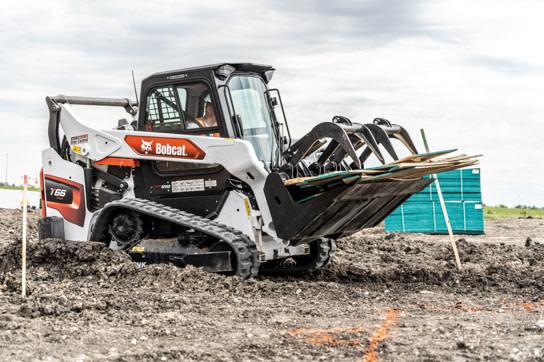 Bobcat T66 clearing debris with a grapple on a graded lot