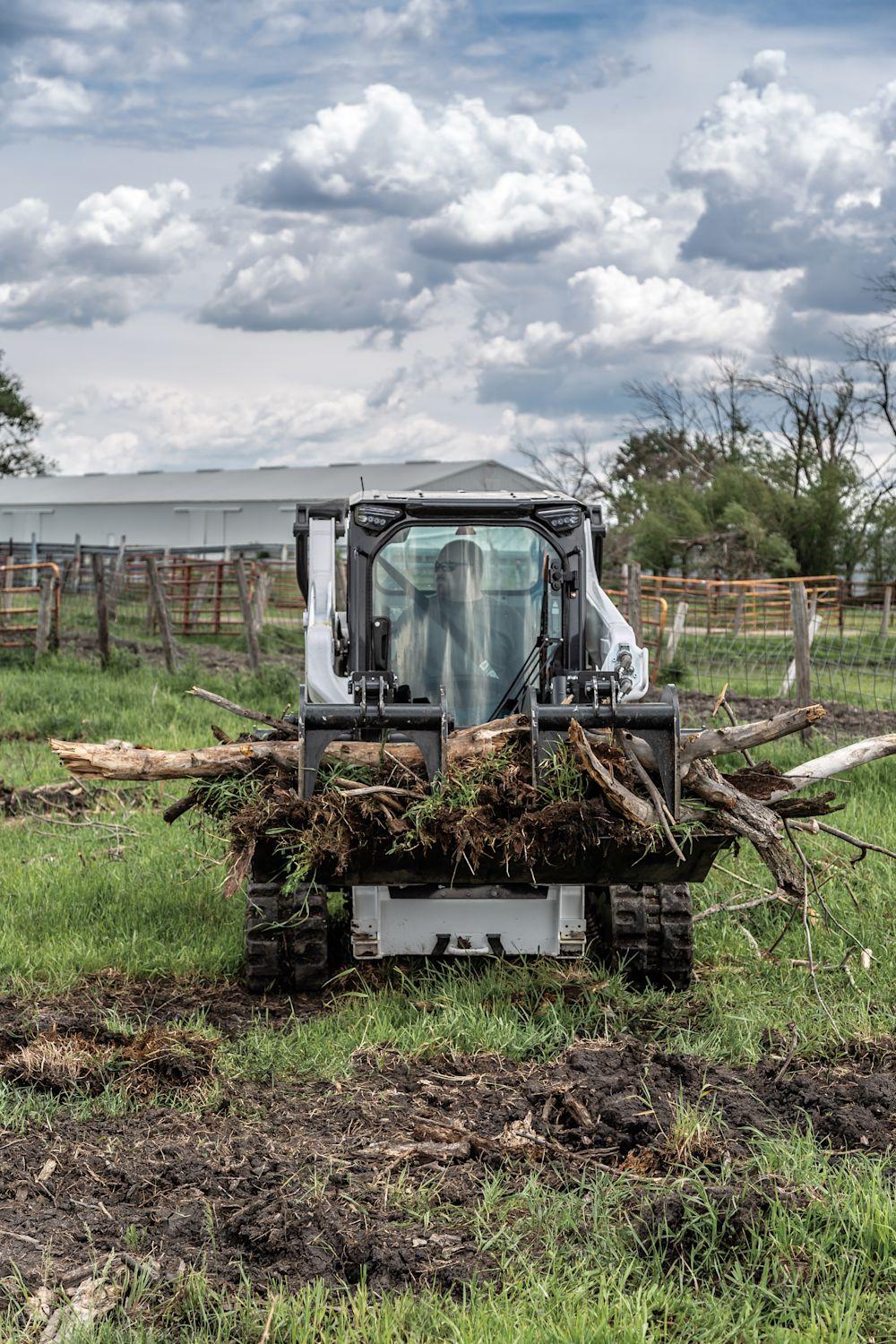 Bobcat T66 carrying cleared brush and logs