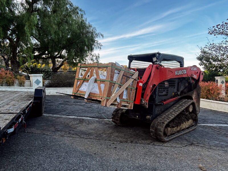 Kubota track loader with pallet forks carrying large crated load