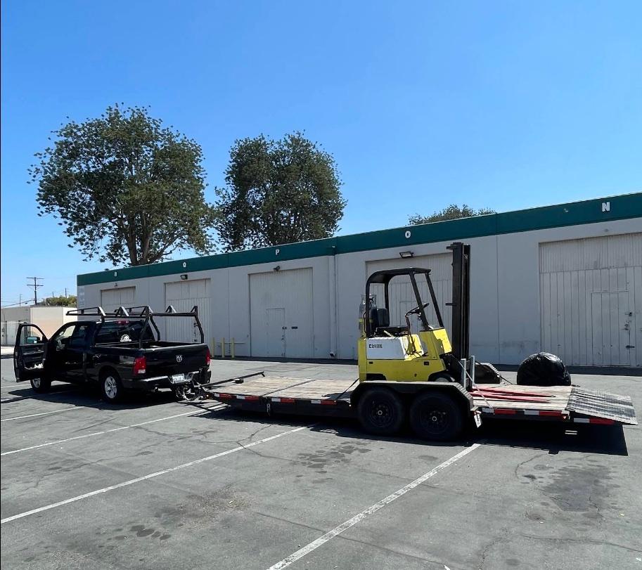 Forklift loaded on the 20-ft tilt trailer, hitched to a pickup for transport