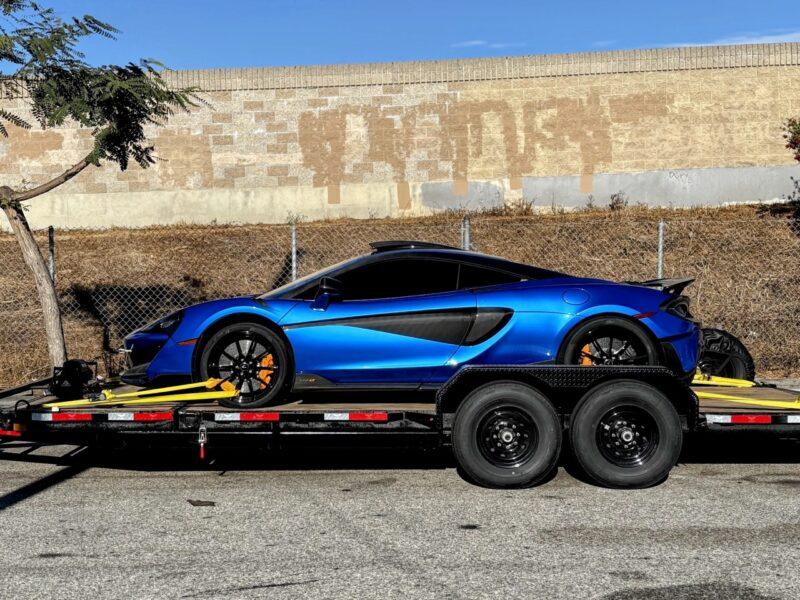 Blue sports car secured on the tandem-axle tilt trailer